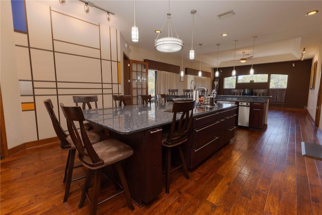 kitchen with a large island, a breakfast bar, visible vents, baseboards, and dark wood-style flooring