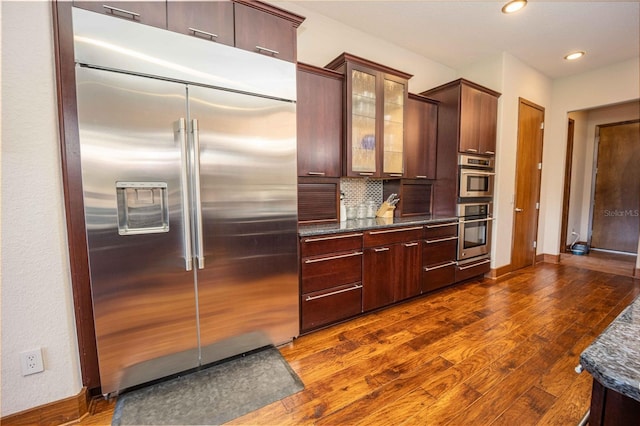 kitchen with glass insert cabinets, appliances with stainless steel finishes, baseboards, and dark wood-style flooring