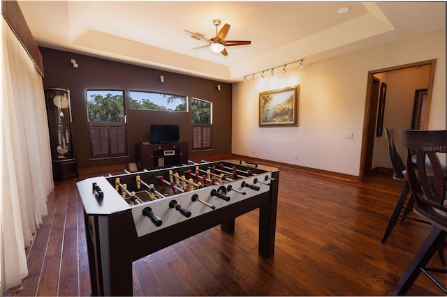 rec room with wood finished floors, a ceiling fan, baseboards, and a raised ceiling