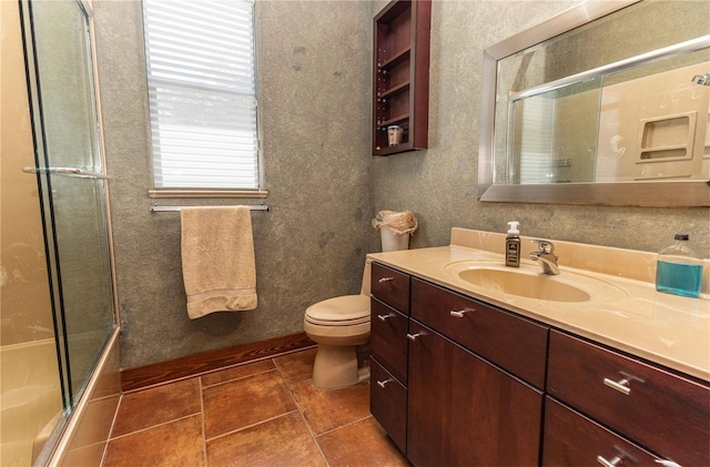 bathroom with combined bath / shower with glass door, vanity, tile patterned floors, and toilet