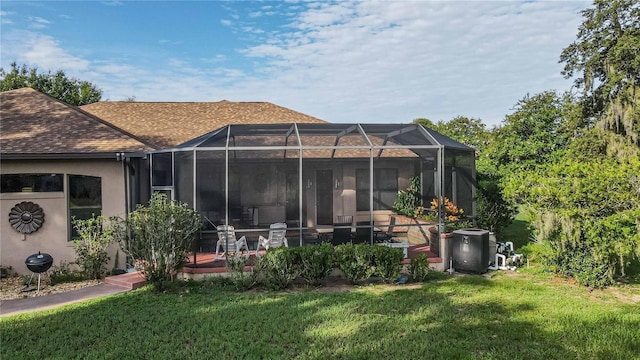 rear view of property with stucco siding, a lanai, a yard, and a shingled roof