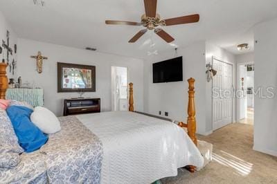 bedroom with a ceiling fan, connected bathroom, and light colored carpet