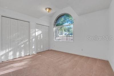 unfurnished room with vaulted ceiling and carpet flooring