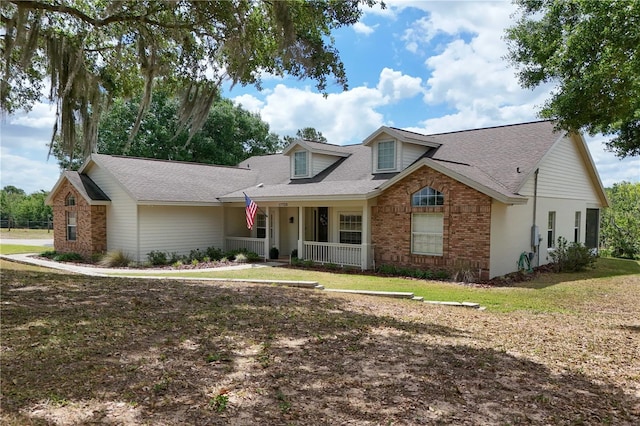 17728 Palm View Cir, Mount Dora, FL 32757 - view of front facade featuring covered porch, brick siding, a front lawn, and roof with shingles