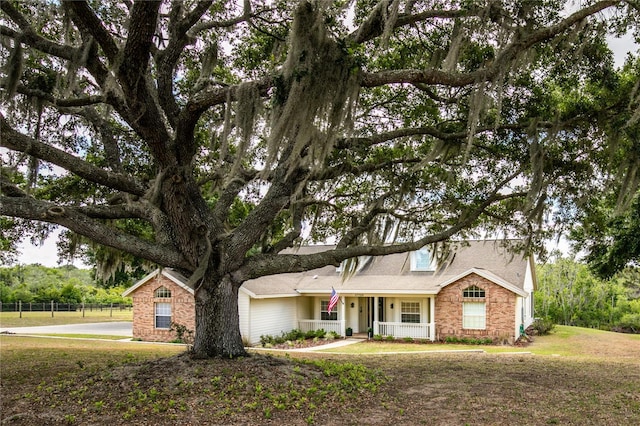 17728 Palm View Cir, Mount Dora, FL 32757 - view of front facade featuring a porch, a front yard, and stone siding