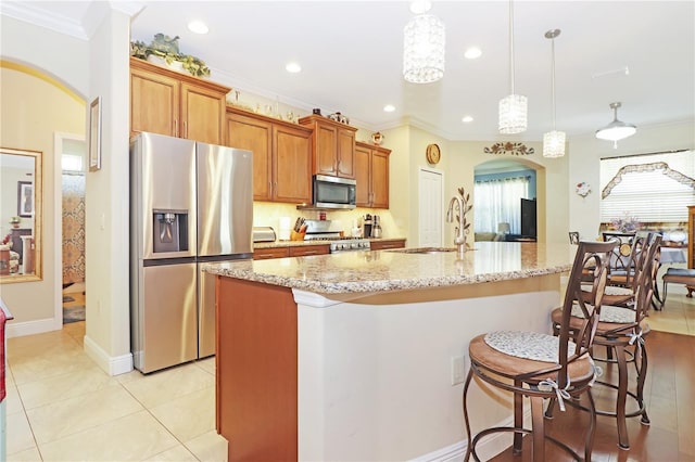 kitchen featuring a sink, arched walkways, appliances with stainless steel finishes, and crown molding