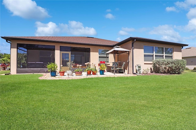 rear view of property featuring a yard, a patio area, a sunroom, and stucco siding