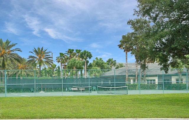 view of sport court with fence and a lawn