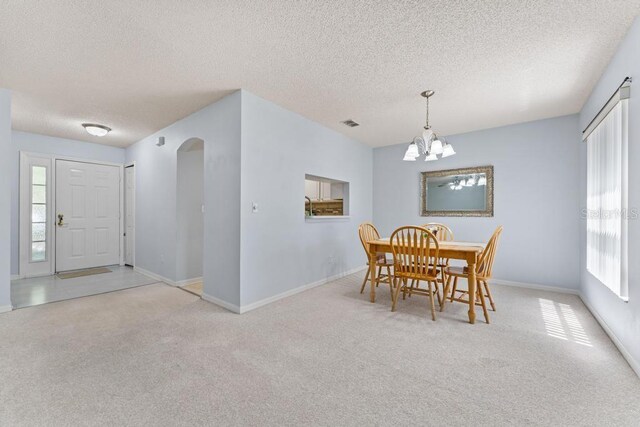 4386 Sambourne St, Clermont, FL 34711 - carpeted dining area featuring arched walkways, a textured ceiling, baseboards, and an inviting chandelier