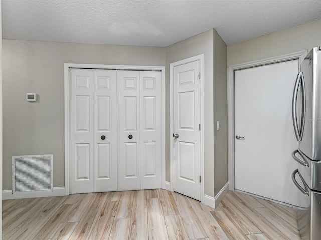 washroom featuring visible vents, a textured ceiling, light wood-style flooring, and baseboards