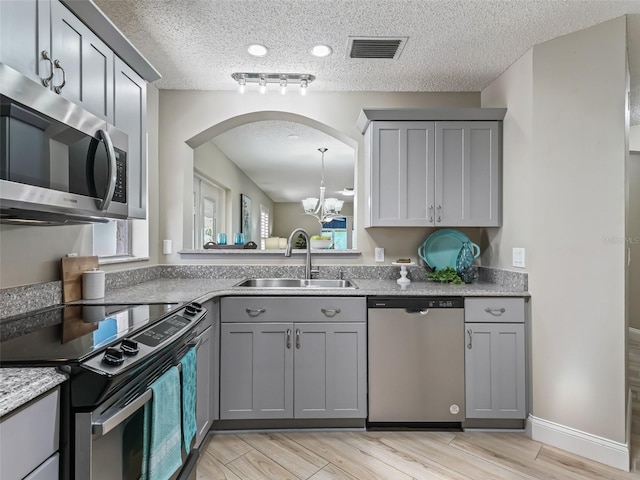 kitchen with visible vents, an inviting chandelier, a sink, gray cabinetry, and stainless steel appliances