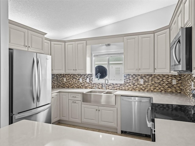 kitchen featuring stainless steel appliances, a sink, light countertops, a textured ceiling, and decorative backsplash