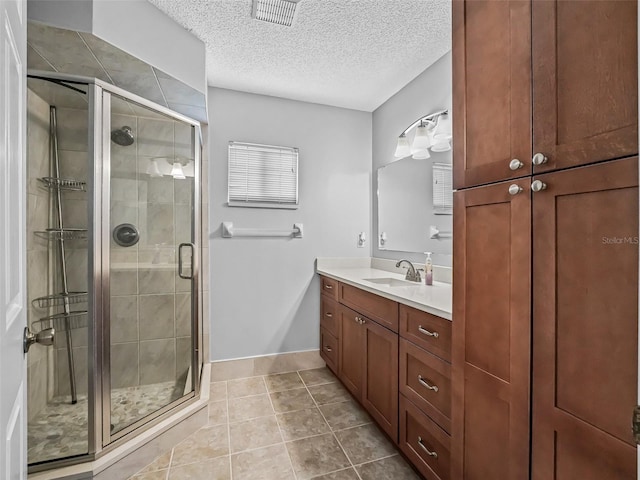 full bath with a shower stall, vanity, a textured ceiling, tile patterned flooring, and baseboards