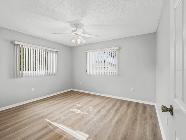 empty room with a ceiling fan, wood finished floors, baseboards, and a textured ceiling