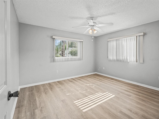 spare room featuring wood finished floors, ceiling fan, baseboards, and a textured ceiling
