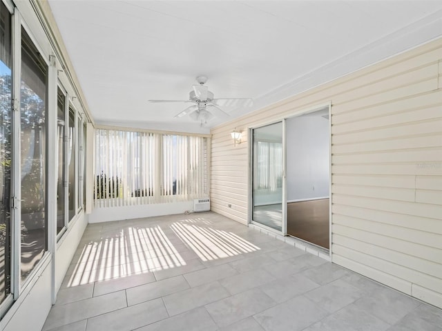 unfurnished sunroom featuring ceiling fan, healthy amount of natural light, and a wall mounted air conditioner