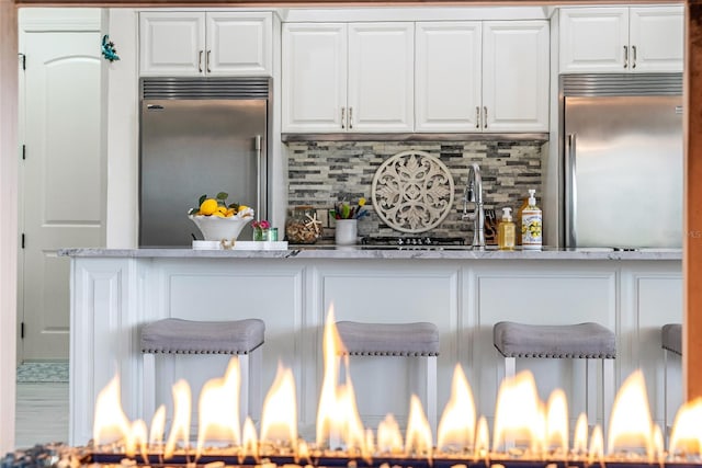 1111 Myrtle Breezes Ct, Fruitland Park, FL 34731 - kitchen featuring stainless steel built in refrigerator, decorative backsplash, white cabinetry, and light stone countertops
