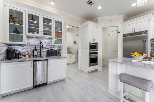 1111 Myrtle Breezes Ct, Fruitland Park, FL 34731 - kitchen featuring built in appliances, white cabinets, light stone counters, tasteful backsplash, and crown molding