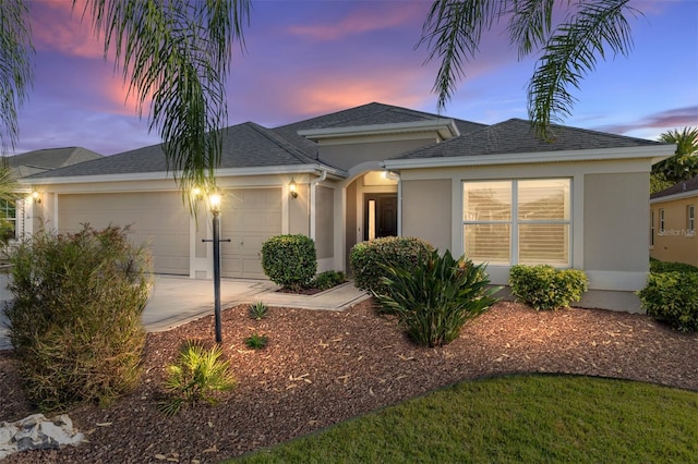 single story home featuring a garage, stucco siding, a shingled roof, and concrete driveway