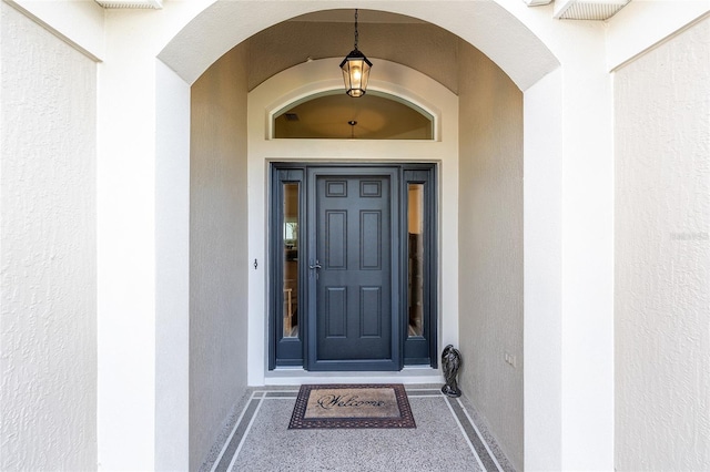view of exterior entry with visible vents and stucco siding