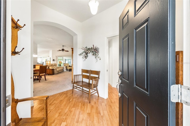foyer with arched walkways, ceiling fan, and light wood-style floors
