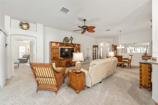 living area featuring arched walkways, light carpet, and visible vents