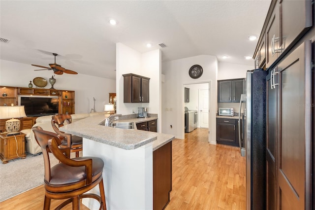 kitchen with a peninsula, lofted ceiling, open floor plan, a kitchen bar, and stainless steel appliances