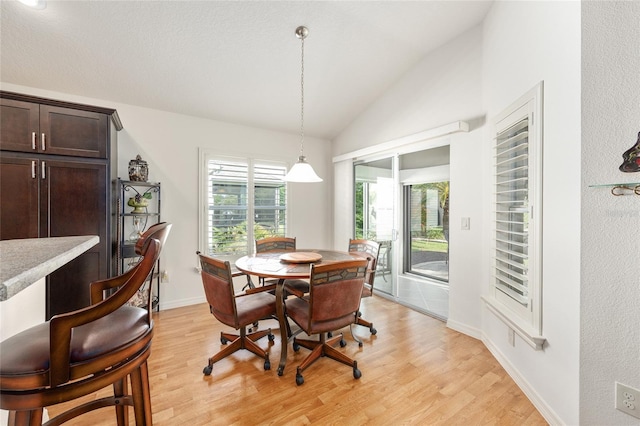 dining area featuring baseboards, light wood-style flooring, and lofted ceiling