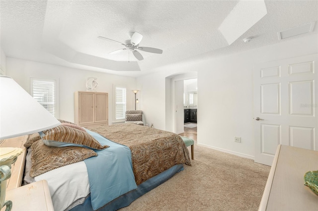 bedroom featuring arched walkways, multiple windows, a textured ceiling, and light colored carpet