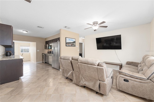 living area with ceiling fan, baseboards, visible vents, and light tile patterned floors