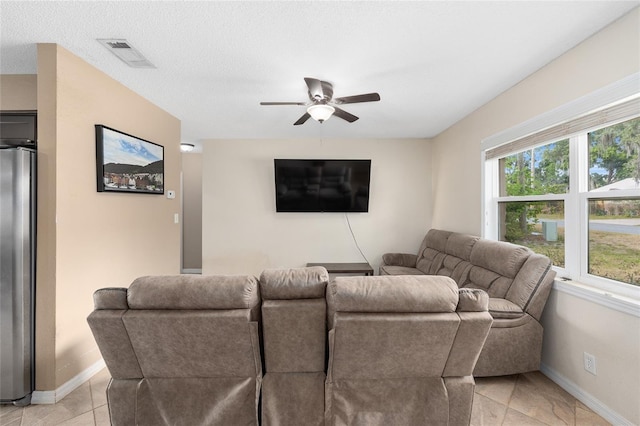 living area with baseboards, visible vents, ceiling fan, and light tile patterned flooring
