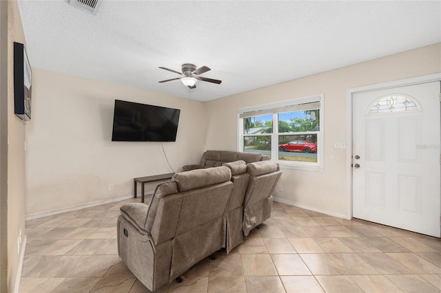 living room with visible vents, a ceiling fan, baseboards, and light tile patterned floors