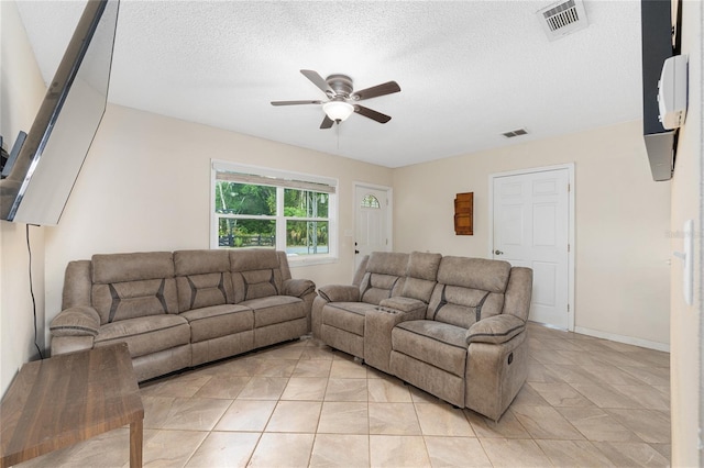 living room featuring ceiling fan, a textured ceiling, visible vents, and light tile patterned floors