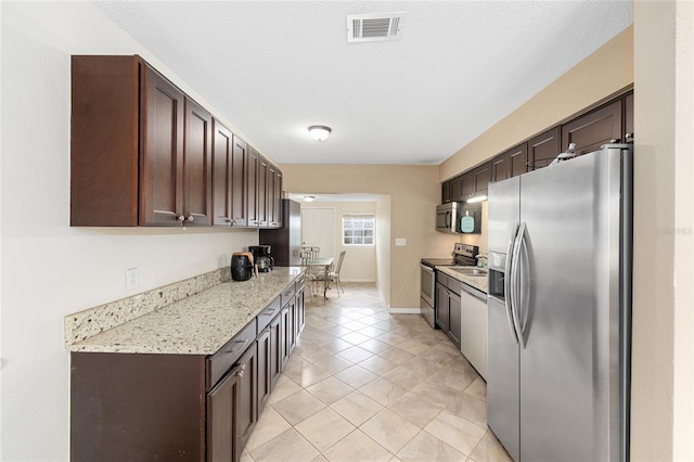 kitchen featuring dark brown cabinets, baseboards, visible vents, appliances with stainless steel finishes, and light tile patterned floors