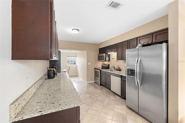 kitchen with a sink, light tile patterned flooring, dark brown cabinetry, stainless steel appliances, and visible vents