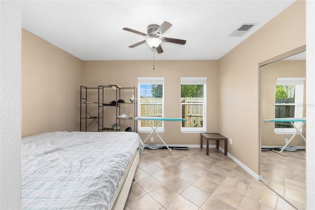 bedroom with visible vents, a ceiling fan, baseboards, and light tile patterned floors