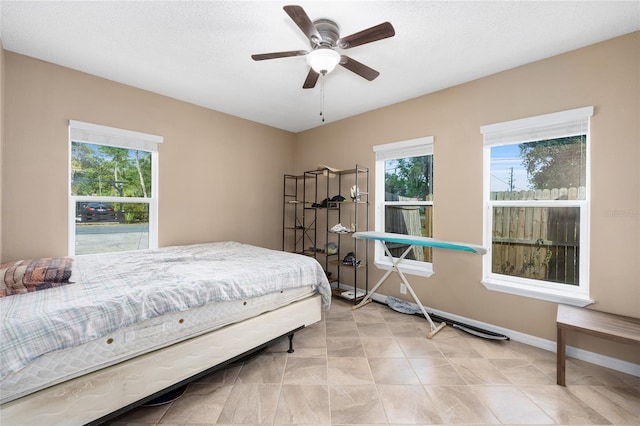 bedroom featuring ceiling fan, baseboards, and multiple windows