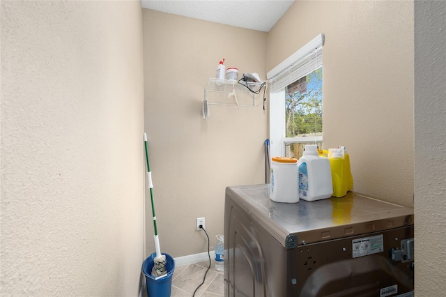 washroom featuring separate washer and dryer, baseboards, tile patterned flooring, and laundry area
