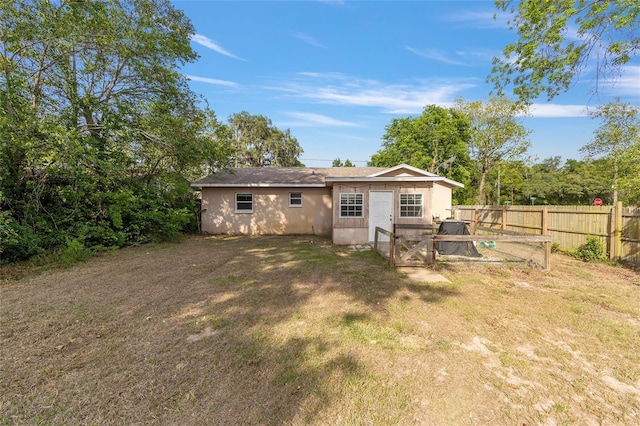 back of property with stucco siding, a yard, and fence