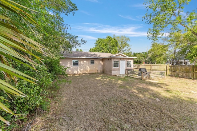 rear view of house featuring stucco siding, a yard, and fence