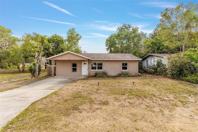 ranch-style house with stucco siding, a carport, a front yard, and concrete driveway