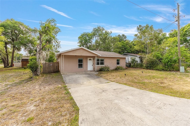 ranch-style home with a front yard, concrete driveway, stucco siding, and fence