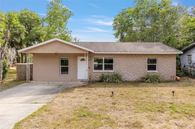 view of front of home with stucco siding, a front lawn, and roof with shingles