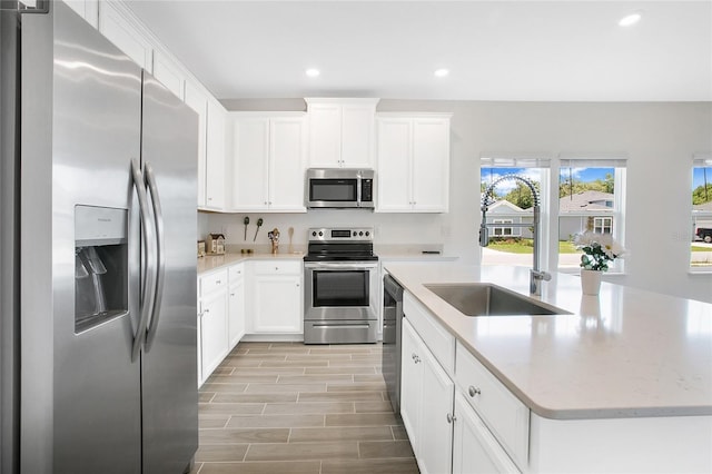 7796 SW 74th Loop, Ocala, FL 34481 - kitchen with white cabinets, a center island with sink, recessed lighting, light wood-style floors, and appliances with stainless steel finishes
