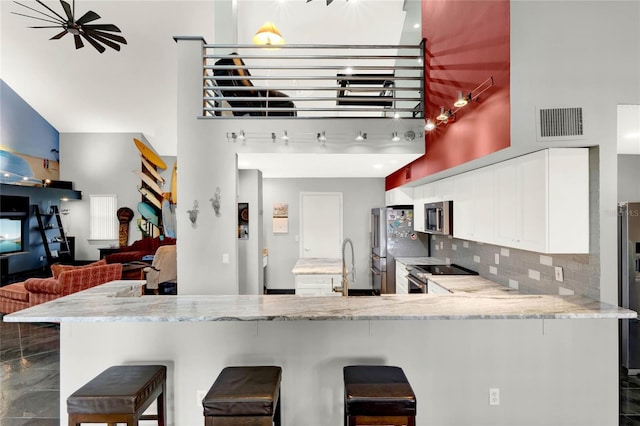 9642 Bear Lake Rd, Apopka, FL 32703 - kitchen featuring appliances with stainless steel finishes, a breakfast bar area, white cabinetry, a towering ceiling, and visible vents