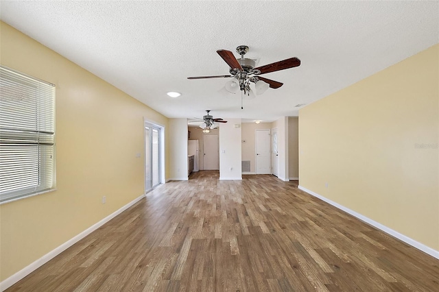 1323 Balboa Ct, The Villages, FL 32159 - unfurnished living room featuring baseboards, wood finished floors, a ceiling fan, and a textured ceiling