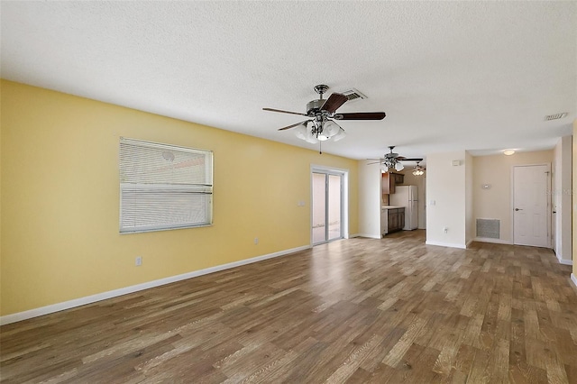 1323 Balboa Ct, The Villages, FL 32159 - unfurnished living room with a ceiling fan, visible vents, wood finished floors, and baseboards