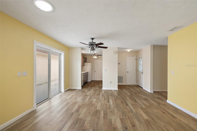 1323 Balboa Ct, The Villages, FL 32159 - unfurnished living room with light wood-type flooring, baseboards, visible vents, a ceiling fan, and a textured ceiling