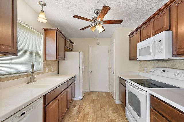 1323 Balboa Ct, The Villages, FL 32159 - kitchen with a sink, light wood-style floors, a ceiling fan, backsplash, and white appliances