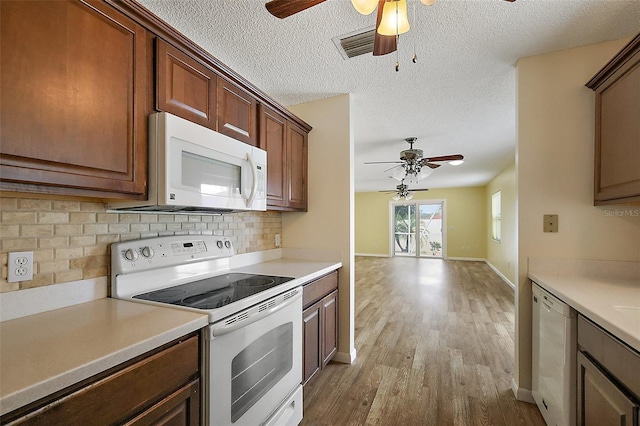 1323 Balboa Ct, The Villages, FL 32159 - kitchen with tasteful backsplash, wood finished floors, white appliances, light countertops, and a ceiling fan